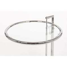 a round glass table with chrome legs and a metal frame around the edge, on a white background