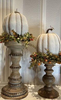 two white pumpkins sitting on top of pedestals