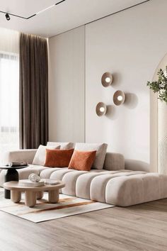 a living room with white walls and wooden flooring is furnished with modern furniture, including a large sectional sofa