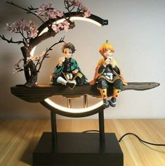 two figurines sitting on top of a table next to a tree and moon