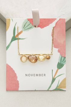 a gold necklace with two hearts on it and the words november written in white letters