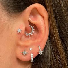 a woman wearing three star and moon shaped piercings on her left behind the ear