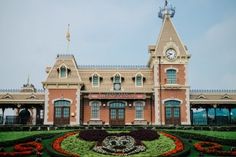 a large building with a clock on the top of it's roof and landscaping around it