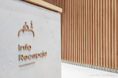 the entrance to an office building with wood slats on the wall and logo in spanish