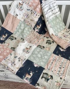 a baby crib bed with a quilt on it's side and an animal themed blanket