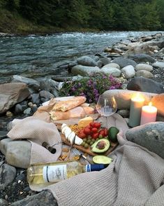 food and wine are laid out on the rocks next to a river