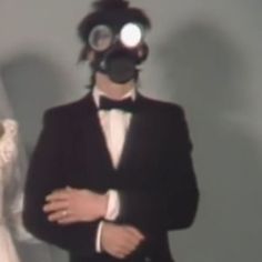 a man in a suit and tie standing next to a woman wearing a mask