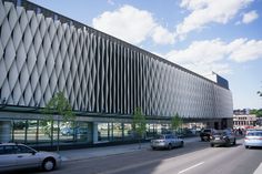 cars are driving down the street in front of a building with an unusual design on it