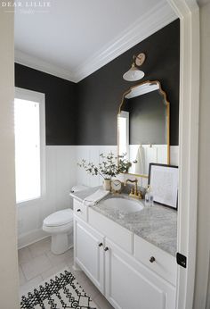 a bathroom with black and white walls, marble counter tops and gold accents