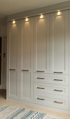 a large white closet with many drawers and lights on the wall above it, along with a rug