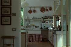 a kitchen with pots and pans hanging from the ceiling, next to an open door