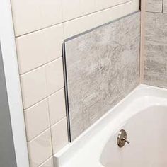 a white bath tub sitting next to a tiled wall