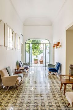 a long hallway with several chairs and tables on either side of the room, leading to an open door