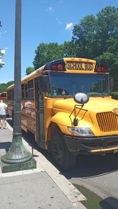 a yellow school bus parked on the side of the road next to a lamp post