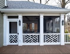 a screened porch with white columns and windows on the side of it, along with a deck