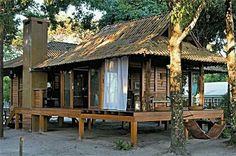 a small wooden house with a hammock hanging from it's front porch