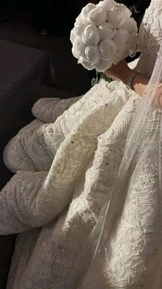 the bride is sitting down in her wedding dress and veil with flowers on her head