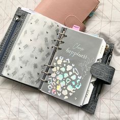 an open planner book sitting on top of a bed next to a wallet and key