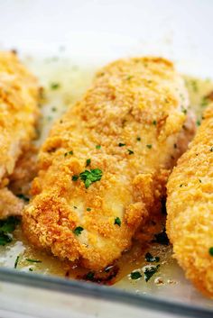 fried chicken with parmesan cheese and herbs in a glass dish on a table