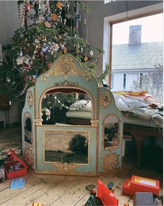 a christmas tree is in the corner of a room with toys and other items on the floor