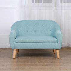 a light blue couch sitting on top of a hard wood floor next to a window