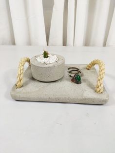 a stone tray with two rings and a ring holder on it, sitting on a white table