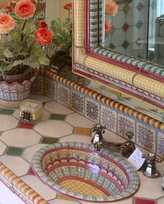 a bathroom sink sitting under a mirror next to a vase with flowers