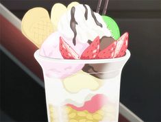 an ice cream sundae in a plastic cup with strawberries and chocolate on top