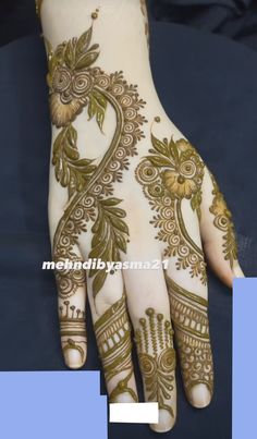 the hand is decorated with gold and white henna designs, which are intricately designed