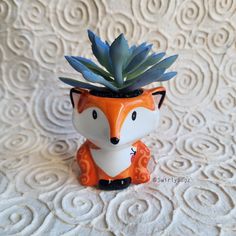 a small ceramic fox planter with a succulent in it's mouth