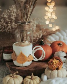 pumpkins and other autumn decorations on a table with candles, coffee cup and mug