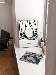 a black and white photo sitting on top of a counter next to a framed poster