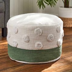 a white pom pom sitting on top of a wooden floor next to a potted plant