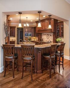 a kitchen with wooden cabinets and an island in the middle, surrounded by bar stools