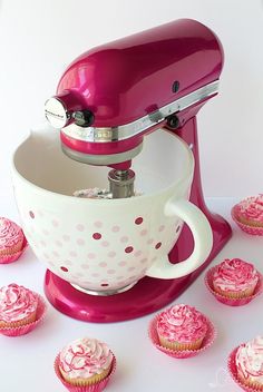 a pink mixer with cupcakes around it