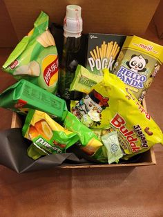 a box filled with snacks and condiments on top of a wooden table next to a bottle