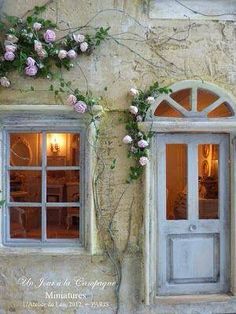 an old building with flowers growing on it's side and the door is open