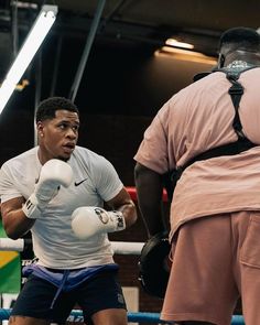 a man standing next to another man wearing boxing gloves