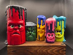 five different colored vases with faces painted on them and one has an evil face