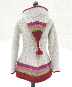 a crocheted sweater on a mannequin with a red and green tassel