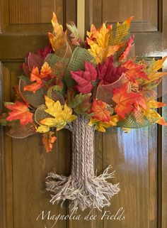 an autumn wreath with leaves and rope hanging on the front door for fall decorating