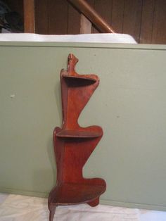 a wooden sculpture sitting on top of a white table next to a green wall and stairs