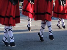 women in red skirts and black stockings walking down the street with their feet on each other