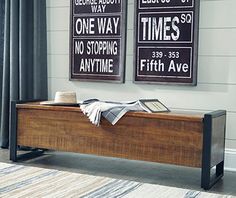 two framed signs on the wall above a bench in a room with a striped rug