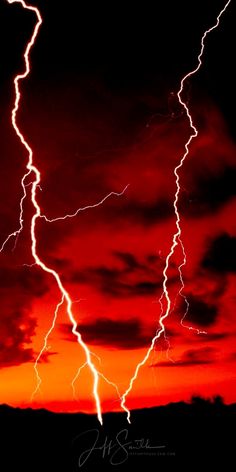 lightning strikes across the sky at night with red and orange clouds in the background photo