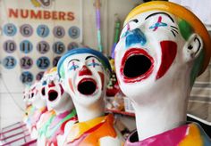 several clown faces painted in different colors and sizes, with numbers on the wall behind them