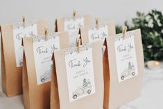 small brown bags with thank you cards attached to them on a table next to a christmas tree