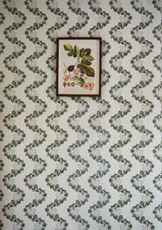 the wall paper is green and white with flowers on it, along with a framed picture