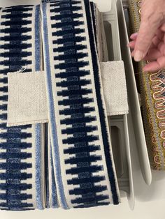 a pair of blue and white pillows on top of a table next to a person's hand