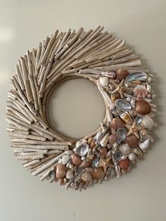 a wreath made out of driftwood sticks and seashells on a white wall